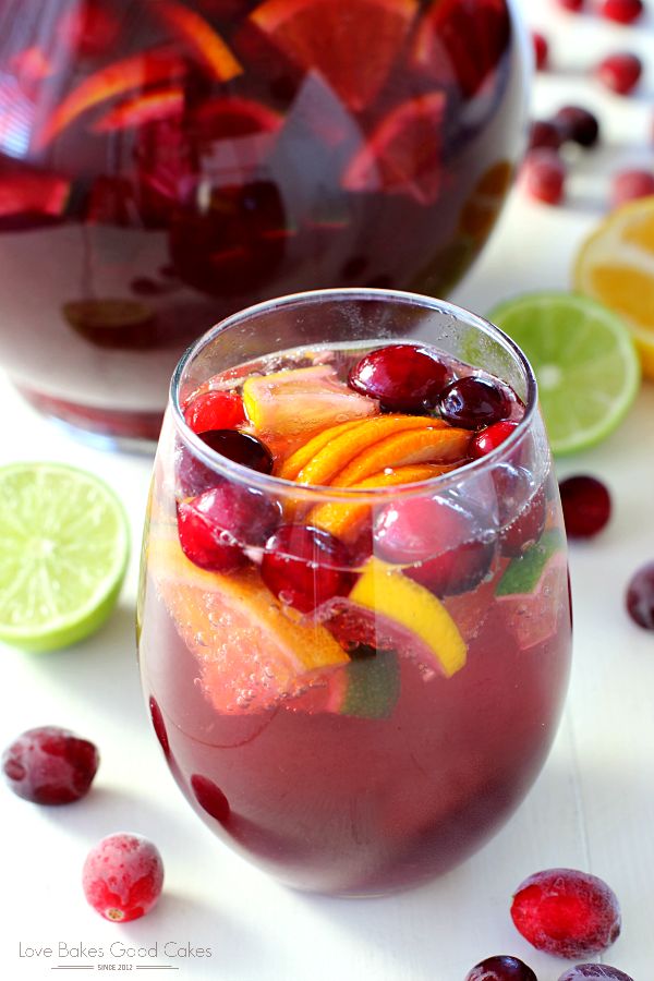 cranberry sangria in a glass with limes and cherries around it