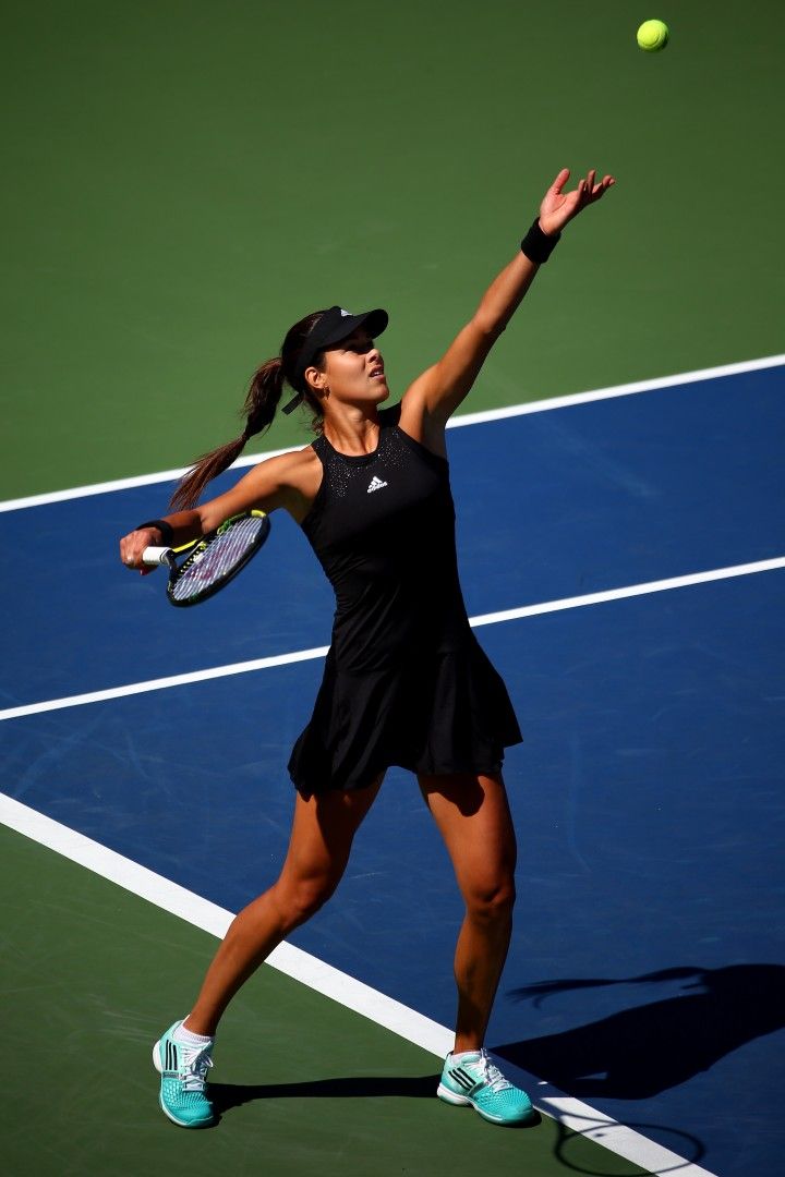 a female tennis player in action on the court with her racquet raised up