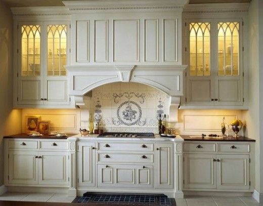 a large kitchen with white cabinets and stained glass window above the stove top, along with an oven