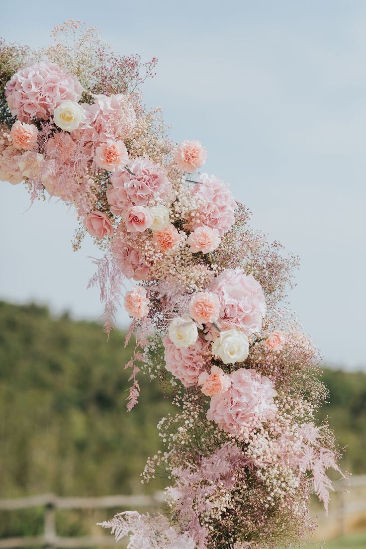 pink and white flowers are hanging from an arch