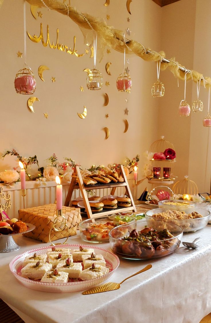 a table topped with lots of food next to a wall filled with hanging lights and decorations