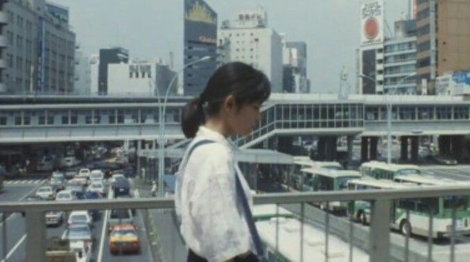 a woman standing on top of a balcony next to a traffic filled cityscape