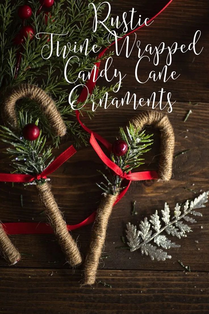 rustic twine wrapped candy cane ornaments on a wooden table with evergreen branches and berries