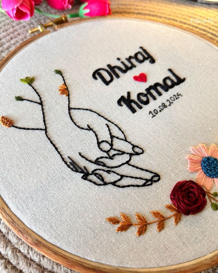 a close up of a embroidery on a wooden hoop with flowers and an embroidered hand