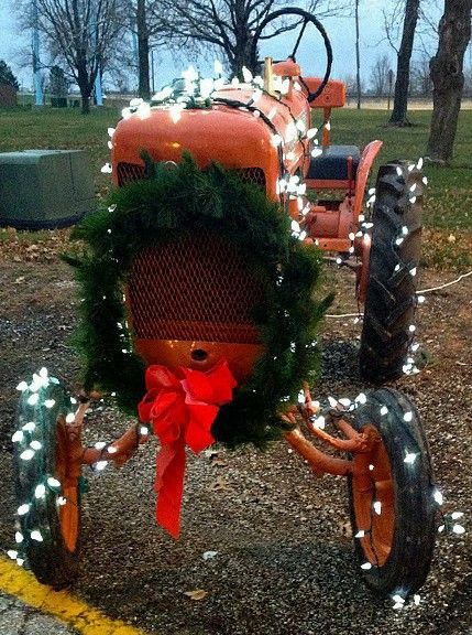 an old tractor decorated with christmas lights and wreath