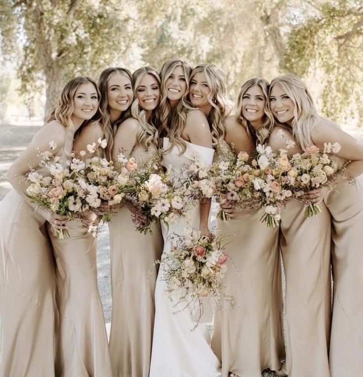 a group of women standing next to each other holding bouquets