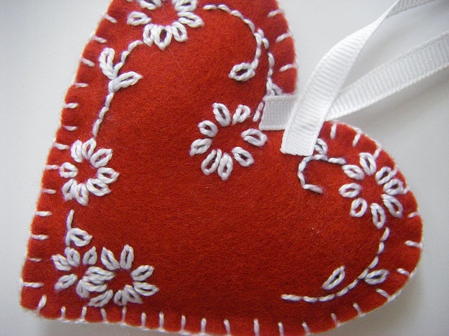 a red heart shaped ornament hanging from a white ribbon