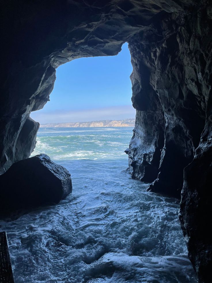 a group of kayakers are in the water through an opening in a cave