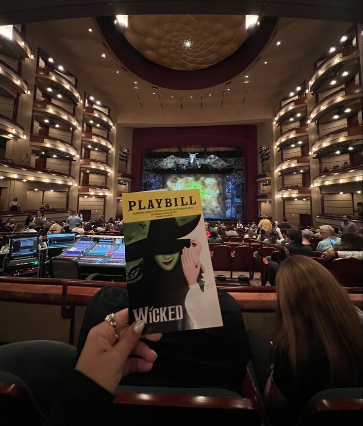 a person holding up a book in front of an auditorium