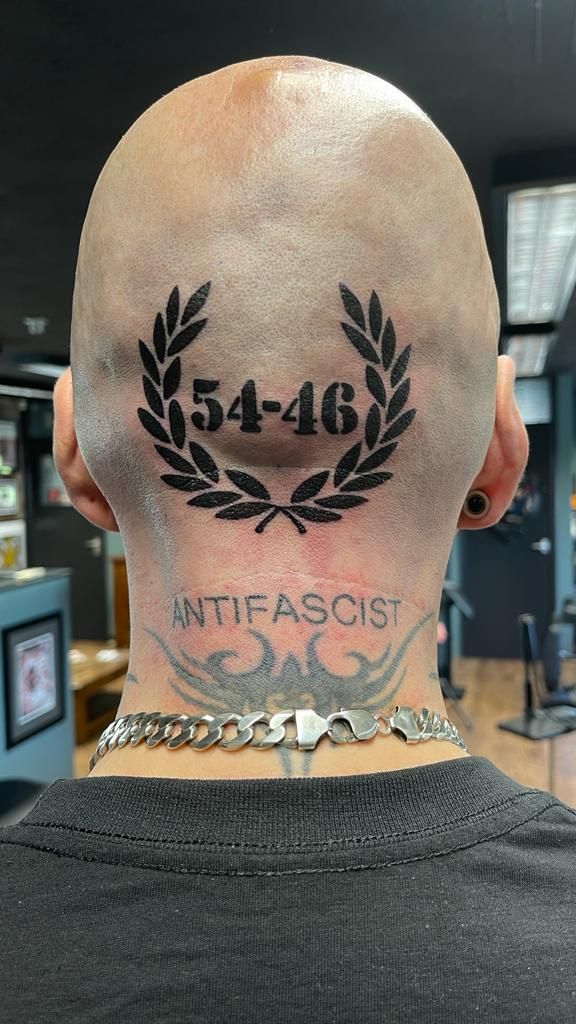 the back of a man's head with tattoos on his neck and number 546