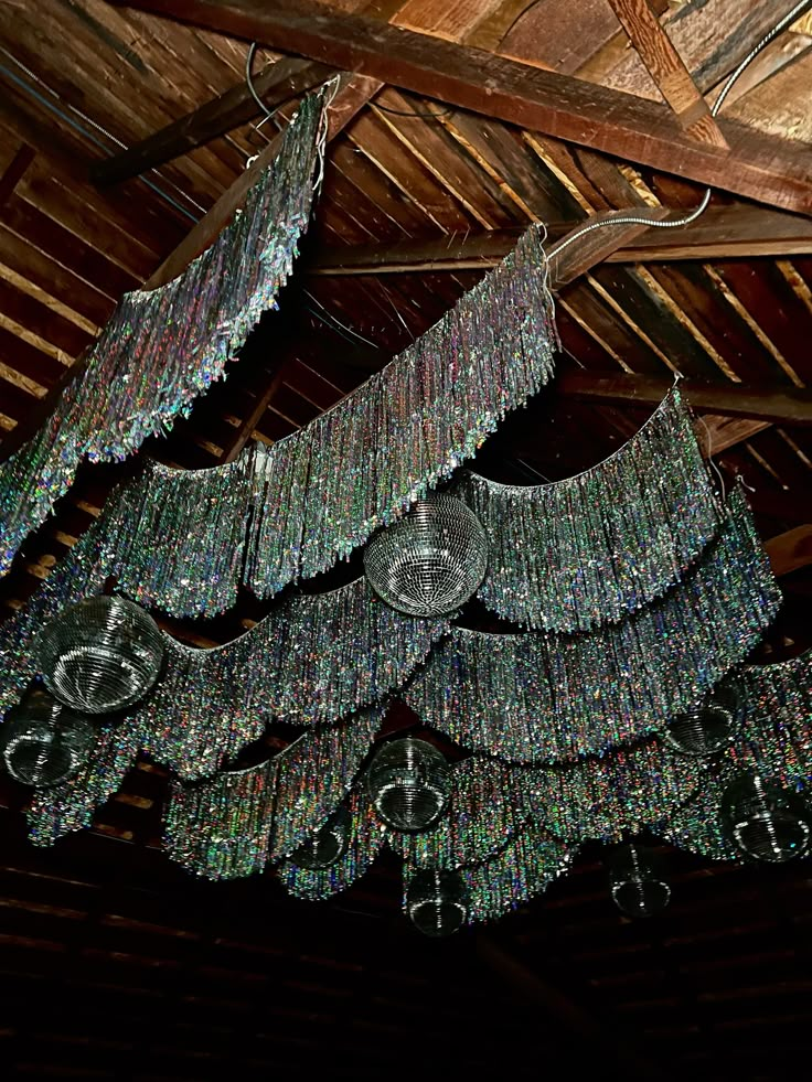 a chandelier hanging from the ceiling in a room with wooden beams and wood flooring