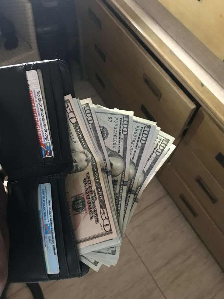 a wallet with money sticking out of it sitting on top of a counter next to a drawer