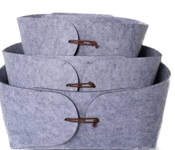 three grey felt storage baskets stacked on top of each other with leather handles and straps