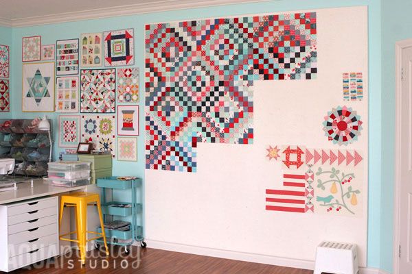 a room with many quilts on the wall