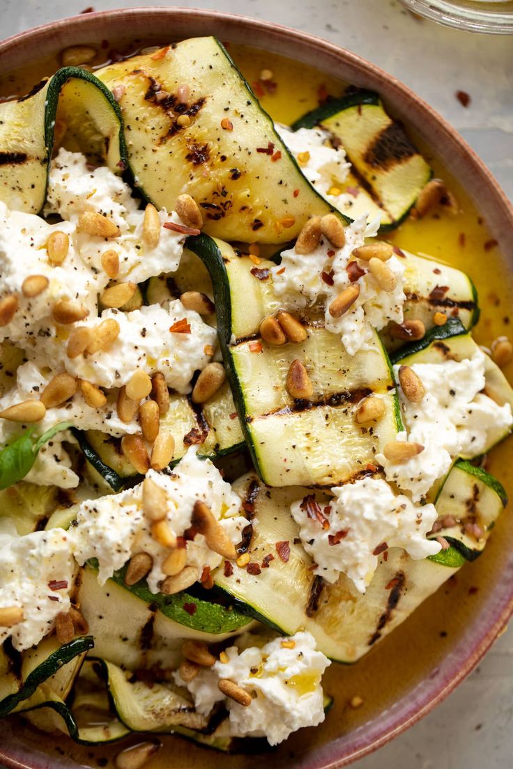 a bowl filled with cucumbers, cheese and nuts