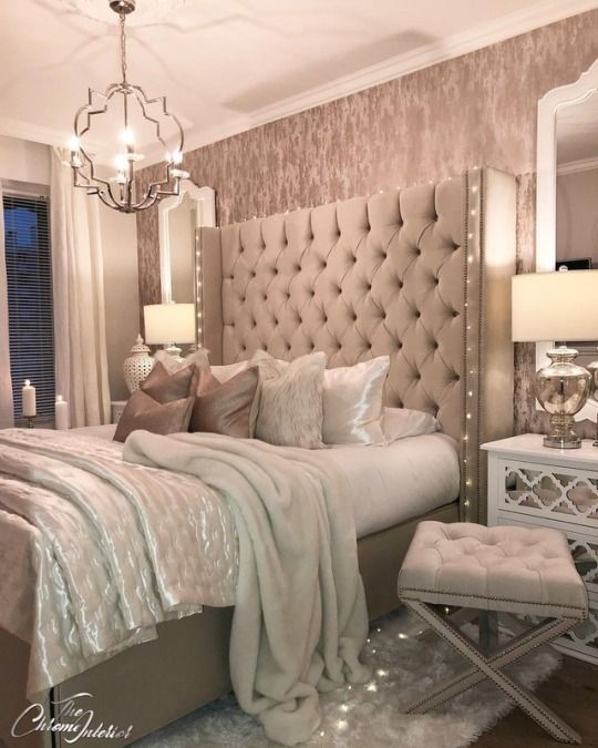 a bedroom with a large bed, mirrored nightstands and chandelier above it