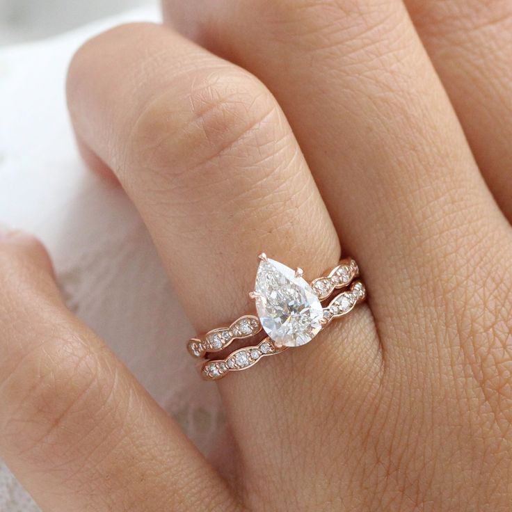 a woman's hand with a diamond ring on top of her finger and the other hand holding an engagement ring