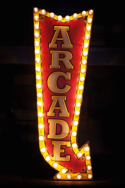 an illuminated sign with the word arcade on it's side in front of a dark background