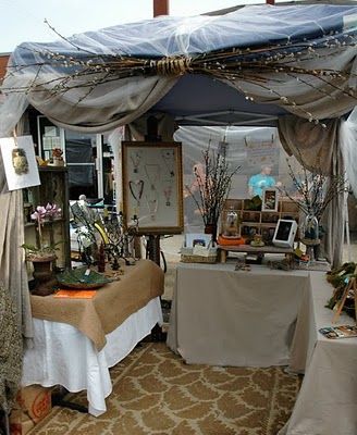 a bed covered in white sheets next to a table with pictures and decorations on it