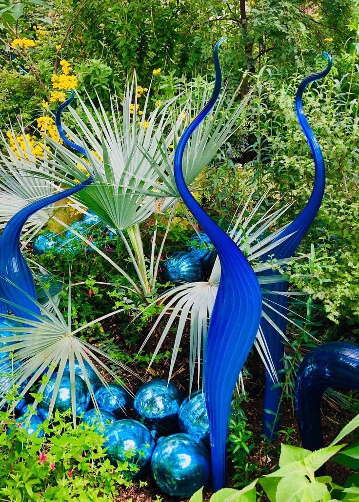 blue glass sculptures in the middle of a garden