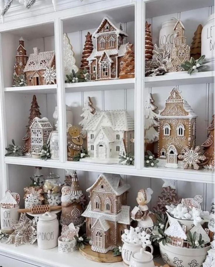 a white shelf filled with christmas decorations and gingerbread houses on top of each other