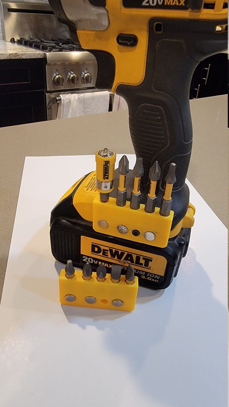 a drill and screwdriver sitting on top of a white table next to each other