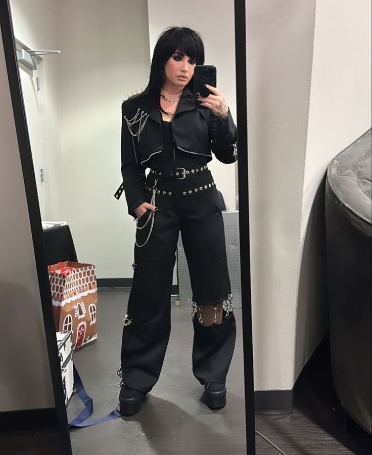 a woman taking a selfie in front of a mirror wearing black clothing and holding a cell phone