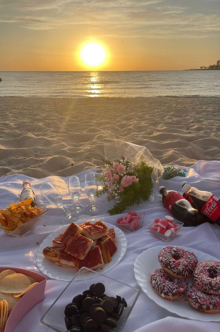 a table with donuts and snacks on it at the beach