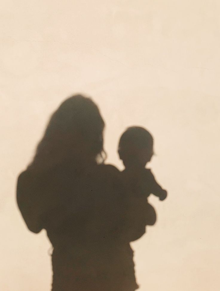 the shadow of a woman holding a baby in her arms