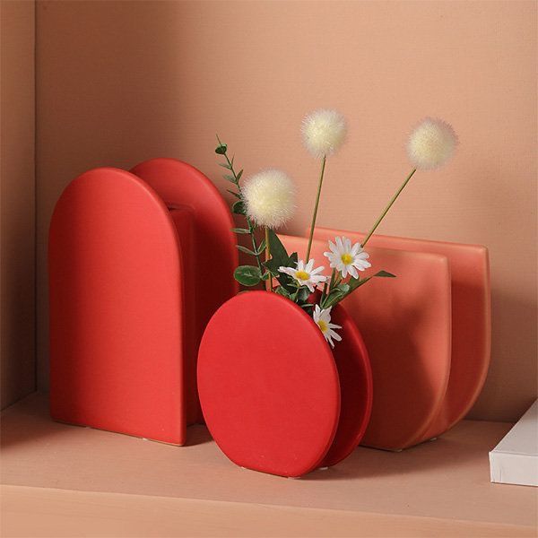 three red vases with flowers in them on a shelf next to a white box