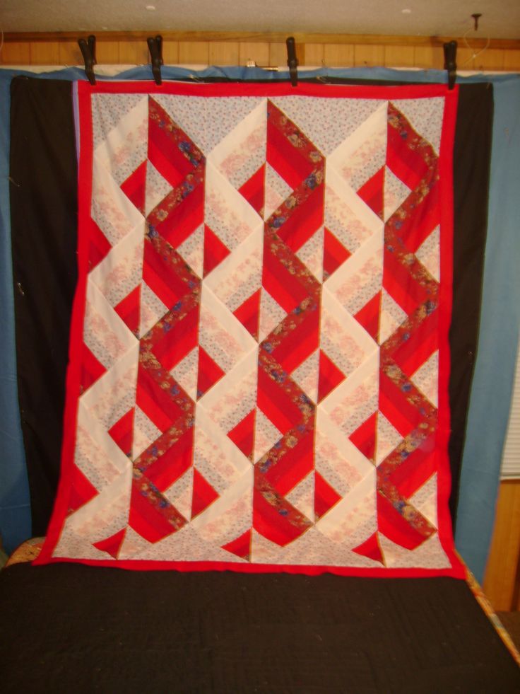 a red and white quilt hanging on a wall