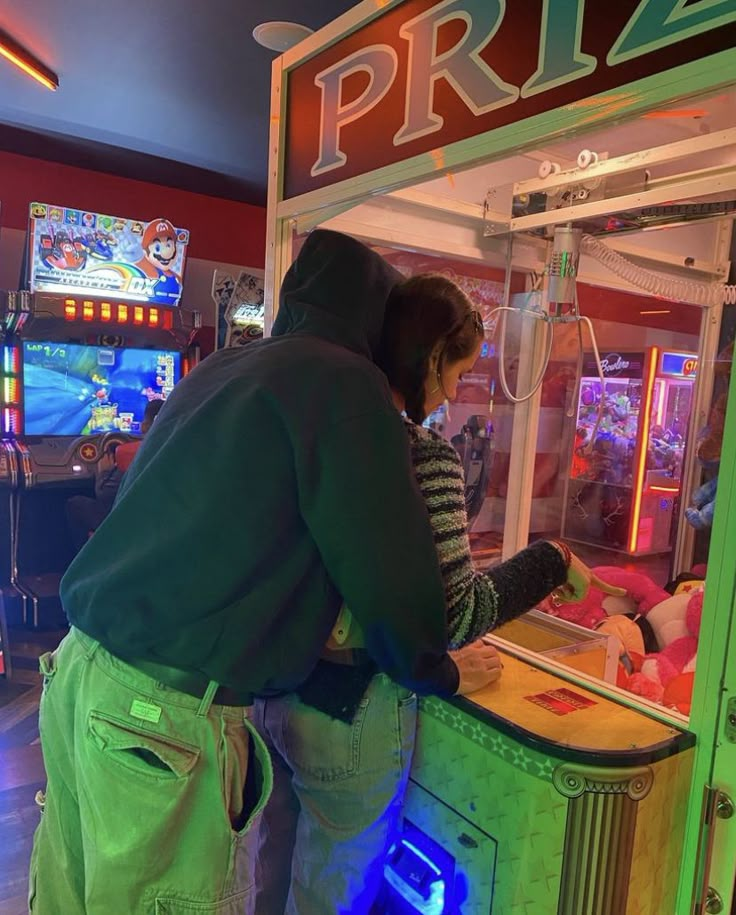 two people standing in front of a vending machine at a game store with neon lights