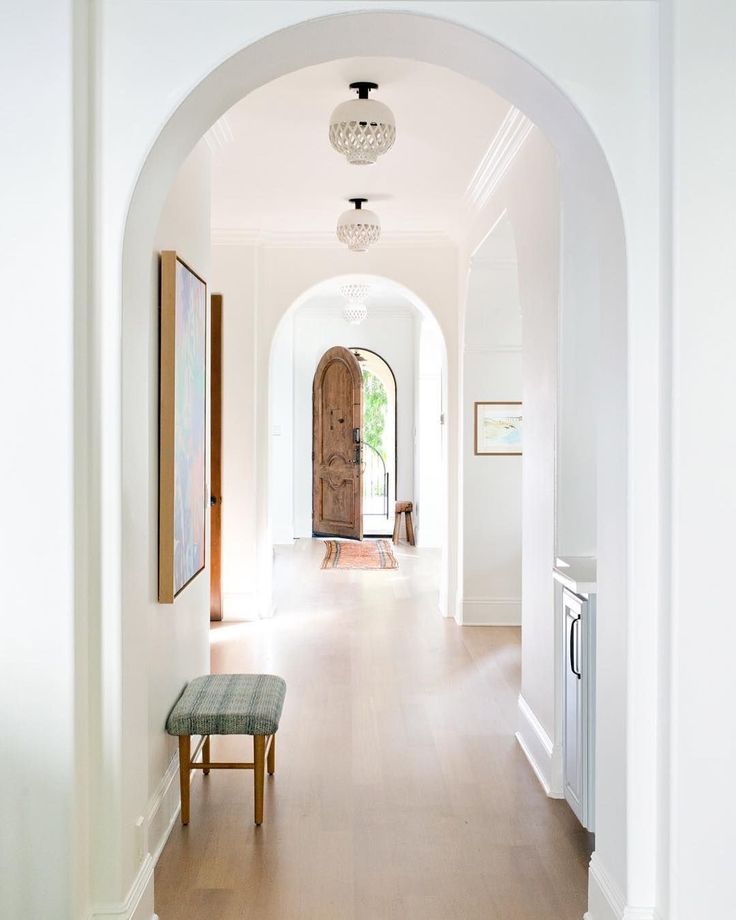 an archway leading to the kitchen and dining room in a house with white walls, wood floors and hardwood flooring