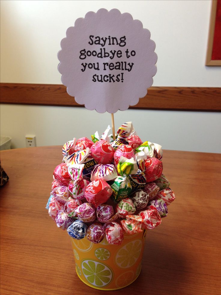 a cup filled with lots of candy sitting on top of a wooden table next to a sign