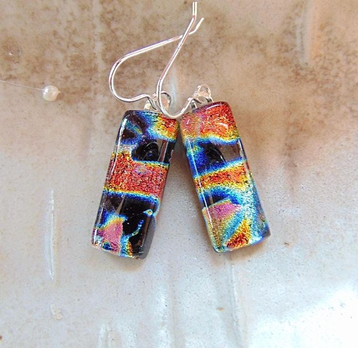 pair of earrings with multicolored glass and silver earwires on white background