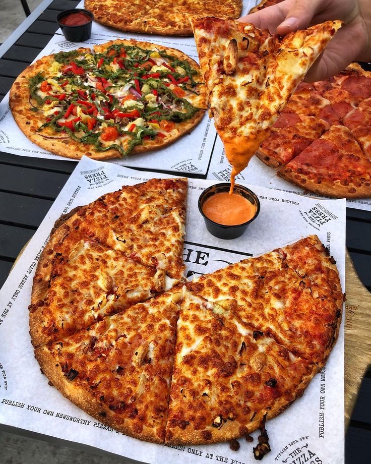 several different types of pizzas sitting on top of napkins with sauce being poured onto them