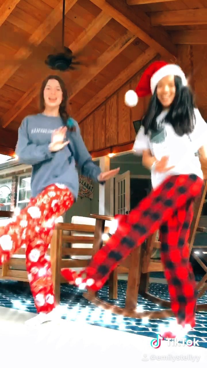 two women in pajamas and santa hats are dancing