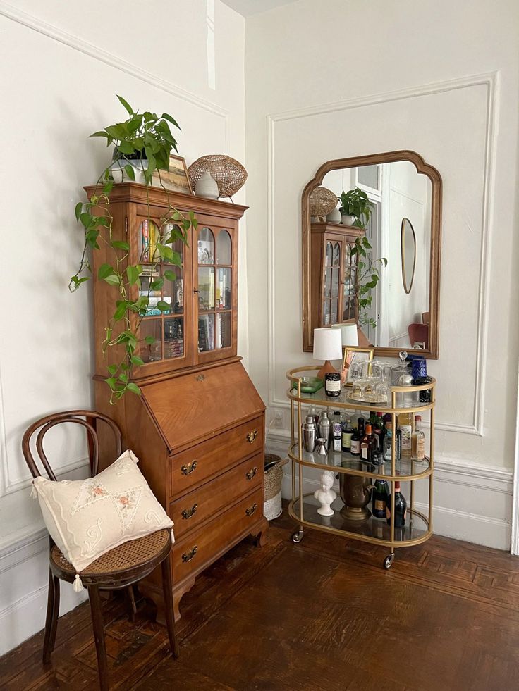 a wooden dresser sitting in the corner of a room next to a mirror and chair