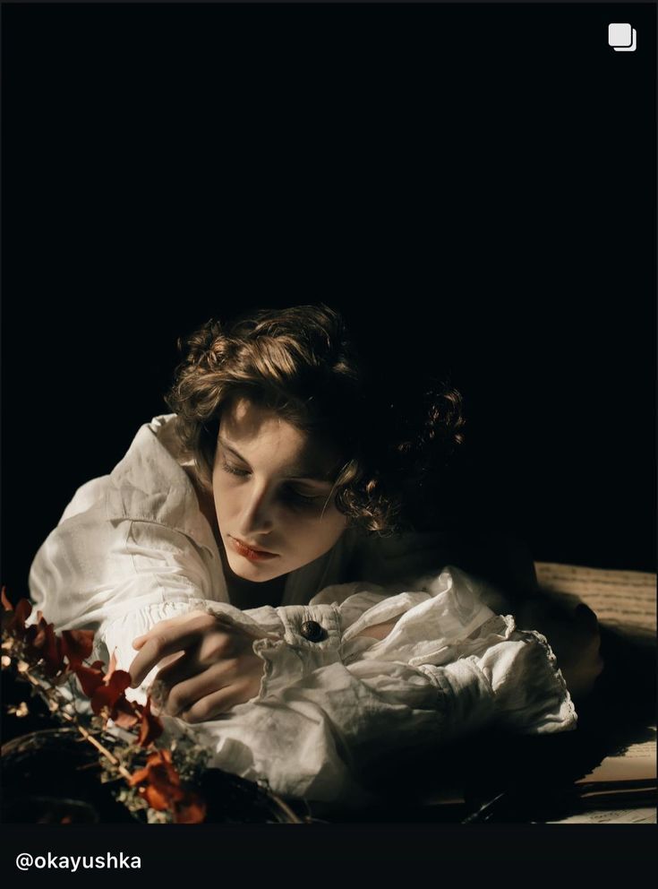 a woman in white shirt laying on floor next to flowers and basket with dried leaves