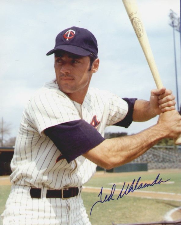 an autographed baseball player holding a bat in his hand and posing for the camera