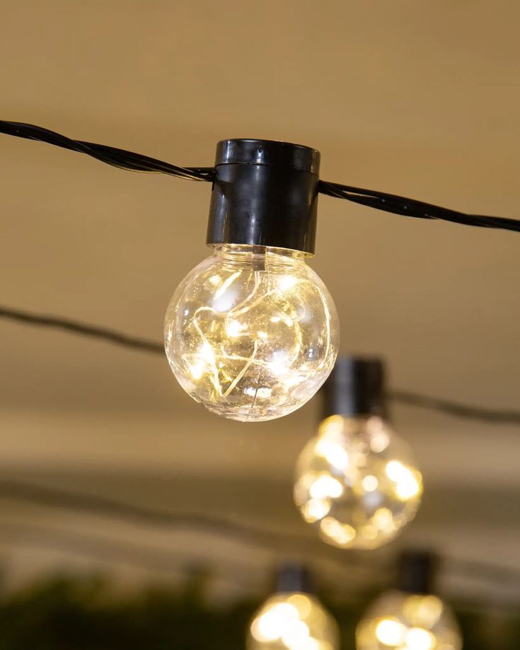 several light bulbs are hanging from a string in an indoor area that is decorated with christmas lights