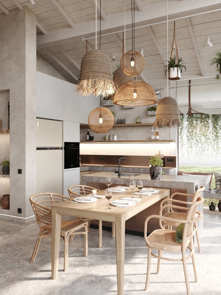 an open kitchen and dining room area with hanging lights above the table, along with wicker chairs