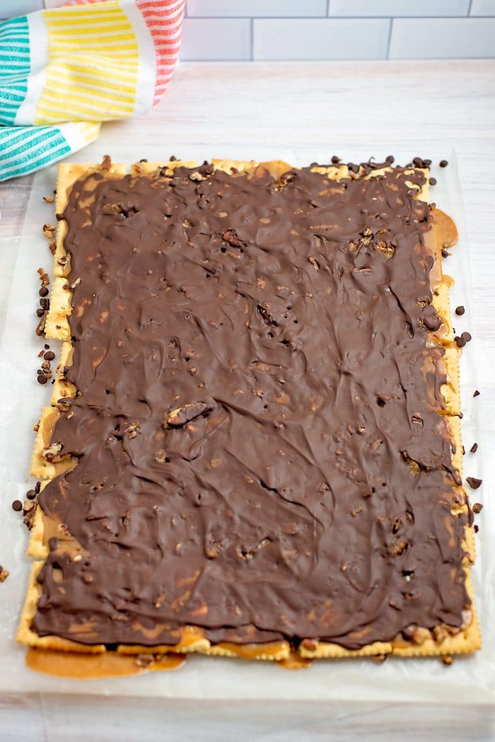 a square cake with chocolate frosting sitting on top of a white counter next to colorful napkins