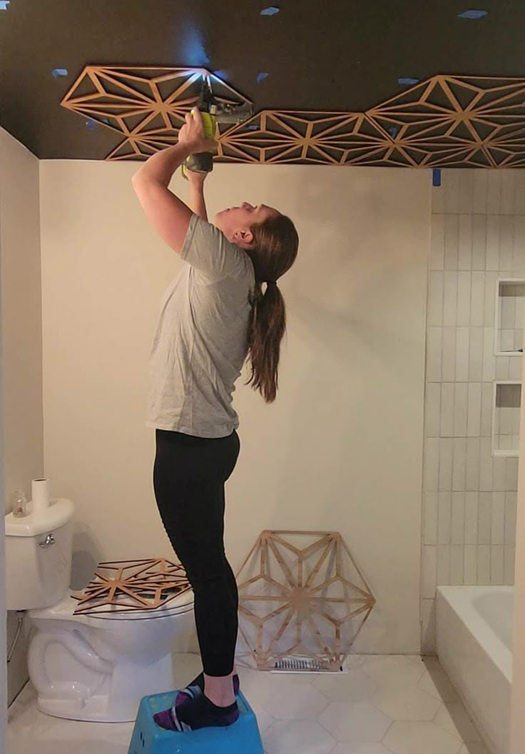 a woman standing on top of a blue object in the middle of a white bathroom