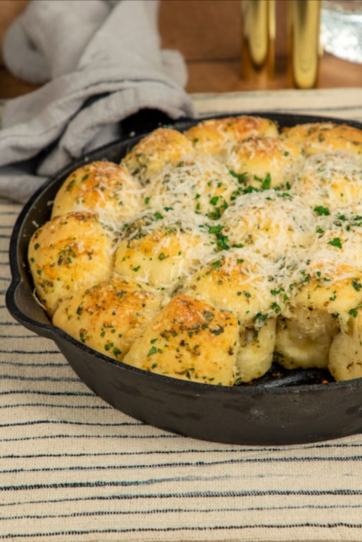 a casserole dish with cheese and herbs in it on a striped place mat