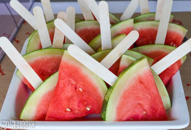 watermelon popsicles with toothpicks in them on a white platter