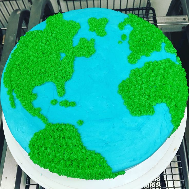 a cake decorated with green grass and the earth on top is sitting on a cooling rack