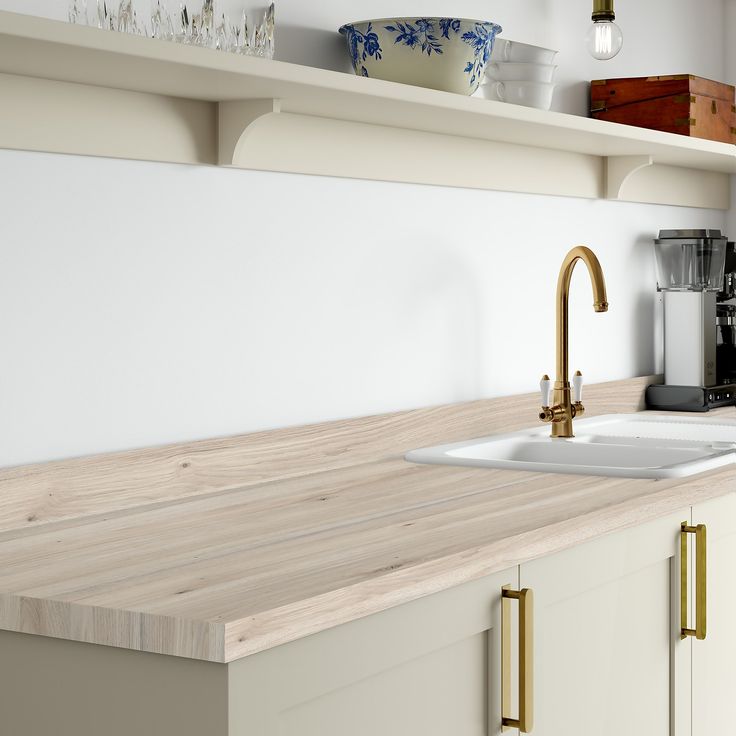 the kitchen counter is made of wood and has brass faucets on each side