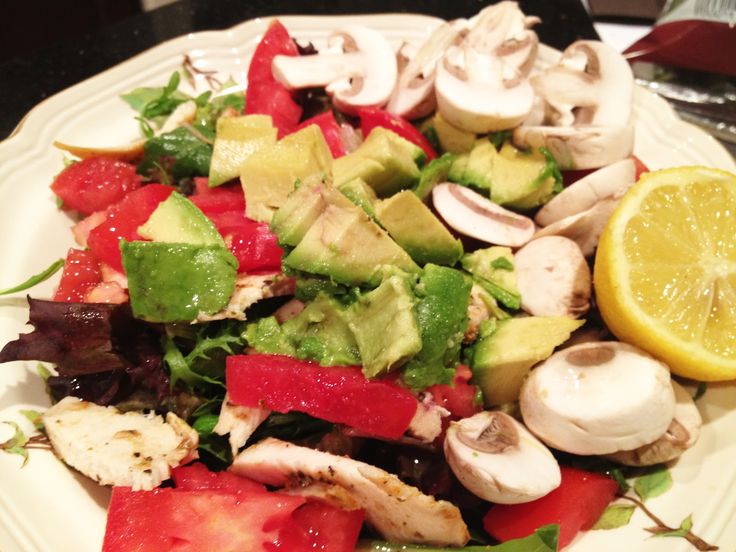 a white plate topped with lots of veggies next to a slice of lemon