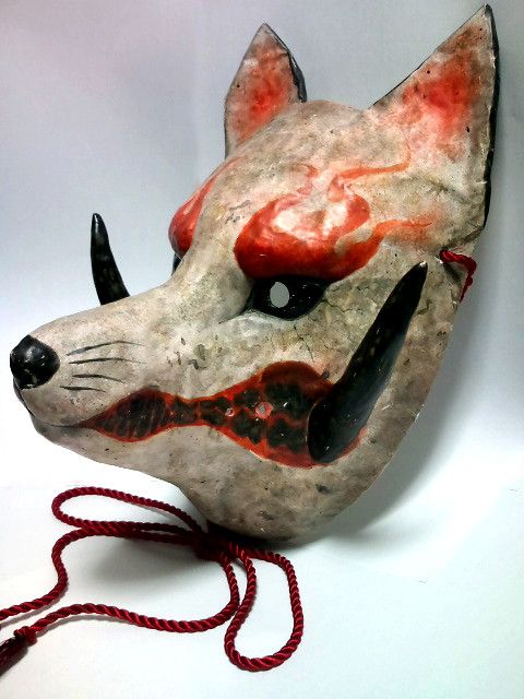 an animal mask is hanging on a red string and it's made out of clay